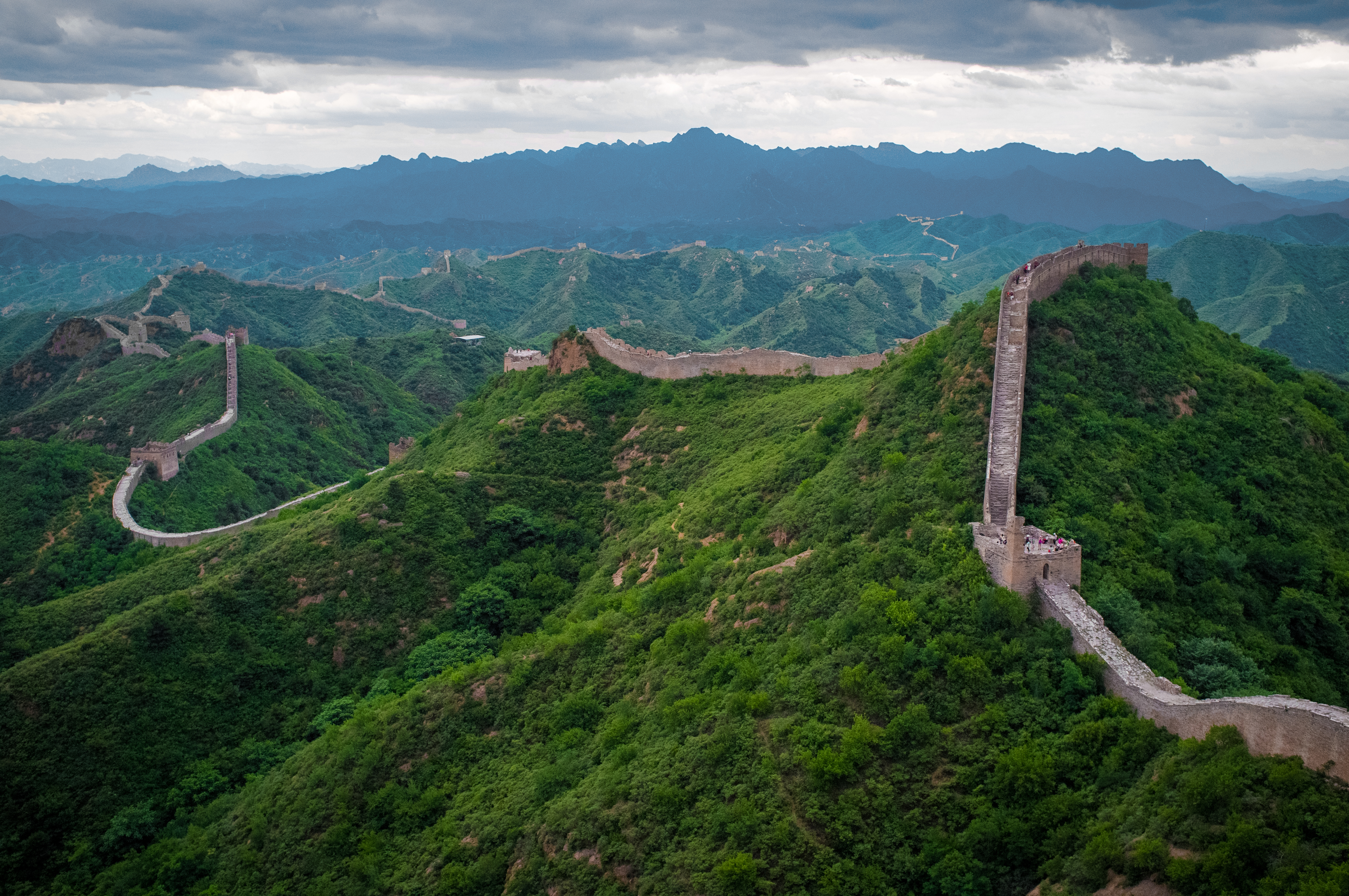 Aerial view of the Great Wall of China winding along forested mountain ridges near Jinshanling
